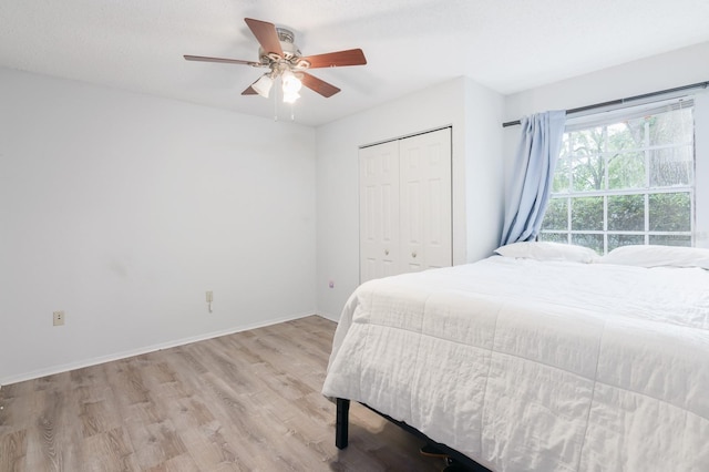 bedroom with light wood-type flooring, ceiling fan, a closet, and a textured ceiling