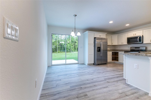 kitchen featuring stainless steel appliances, white cabinetry, hanging light fixtures, and a notable chandelier