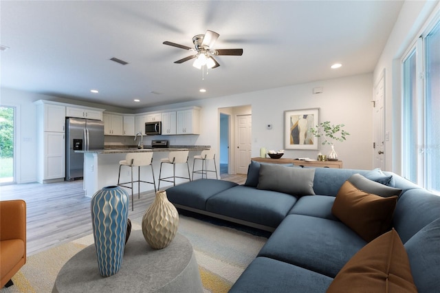 living room featuring ceiling fan and light hardwood / wood-style floors