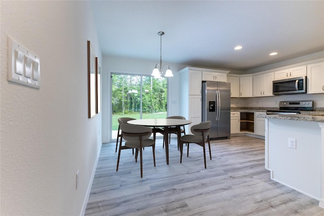 kitchen featuring an inviting chandelier, appliances with stainless steel finishes, white cabinetry, and hanging light fixtures