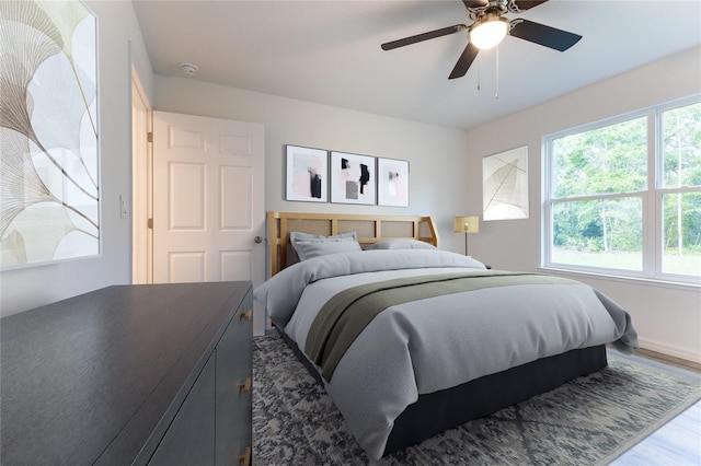 bedroom with ceiling fan, wood-type flooring, and multiple windows