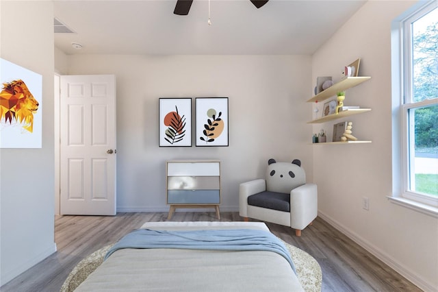 bedroom with ceiling fan, multiple windows, and light hardwood / wood-style flooring