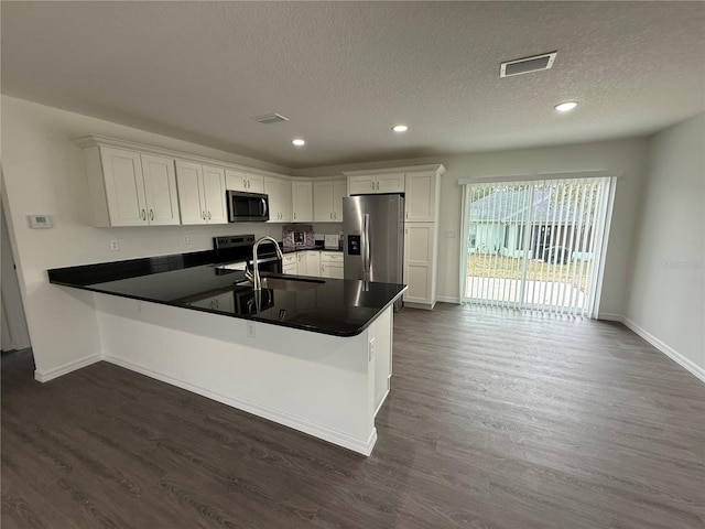 kitchen featuring white cabinetry, kitchen peninsula, stainless steel appliances, a textured ceiling, and sink