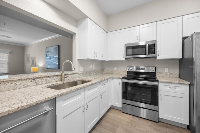 kitchen with stainless steel appliances, crown molding, sink, white cabinetry, and light stone counters