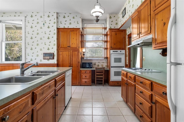 kitchen with light tile patterned flooring, white appliances, hanging light fixtures, and sink