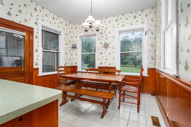 tiled dining area with an inviting chandelier and wooden walls