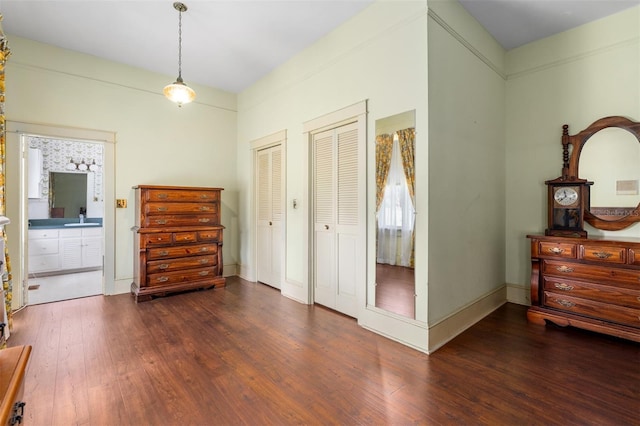 bedroom featuring dark hardwood / wood-style floors, multiple closets, and sink