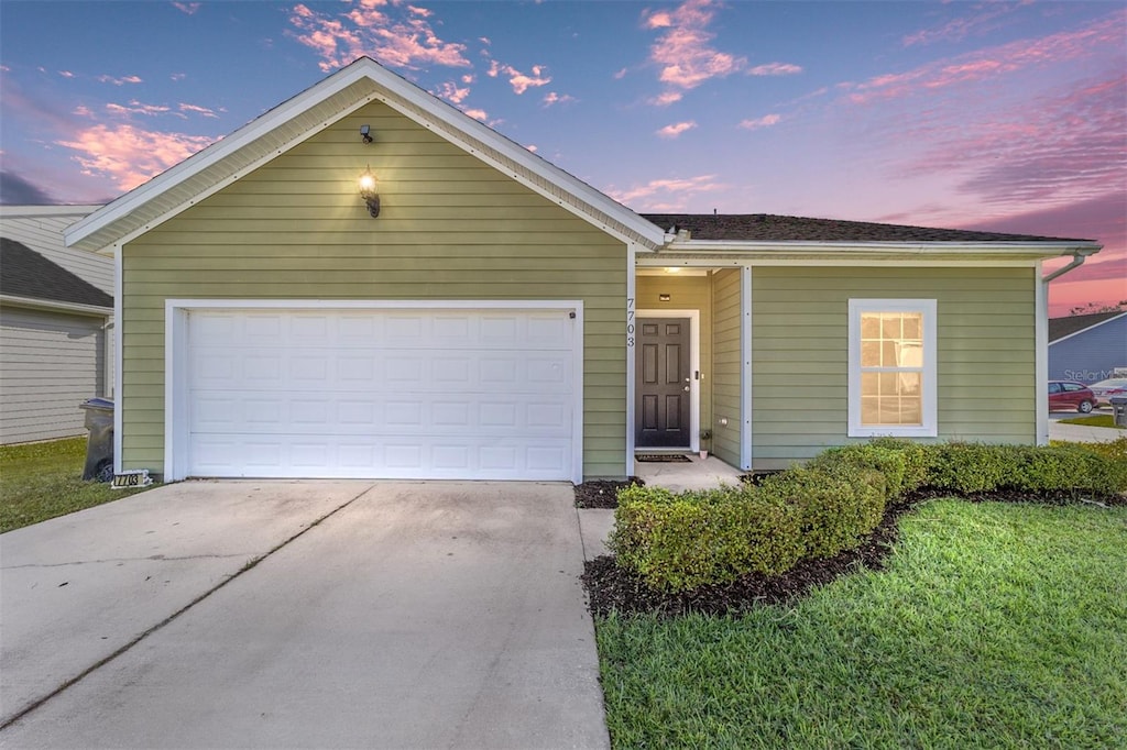 ranch-style house featuring a lawn and a garage