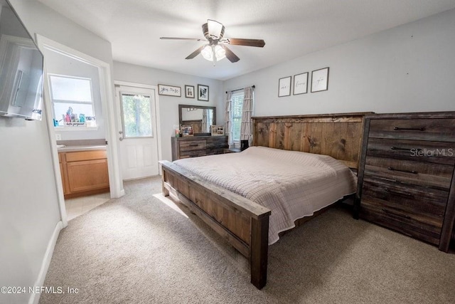 carpeted bedroom featuring ensuite bath and ceiling fan