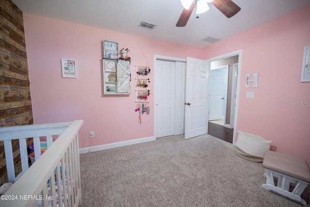 unfurnished bedroom with ceiling fan, a closet, carpet, and a crib