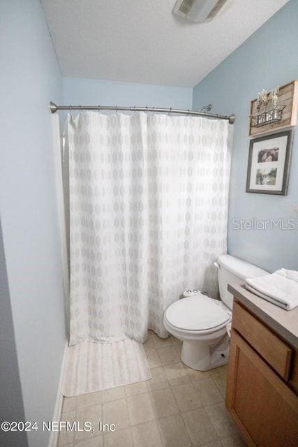 bathroom with walk in shower, vanity, and toilet