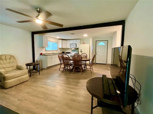 dining area with ceiling fan, light wood-type flooring, and sink