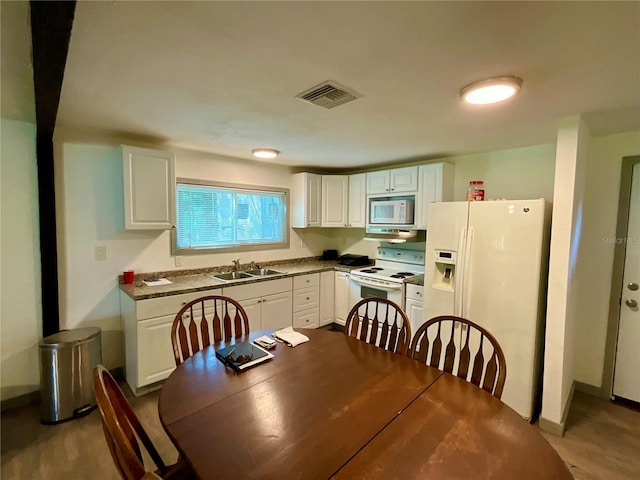 kitchen featuring light wood-type flooring, light stone countertops, white cabinets, white appliances, and sink