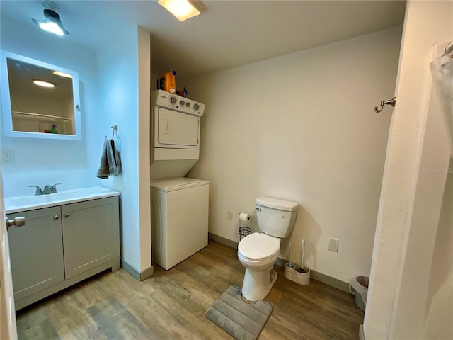 bathroom with toilet, stacked washing maching and dryer, wood-type flooring, and vanity