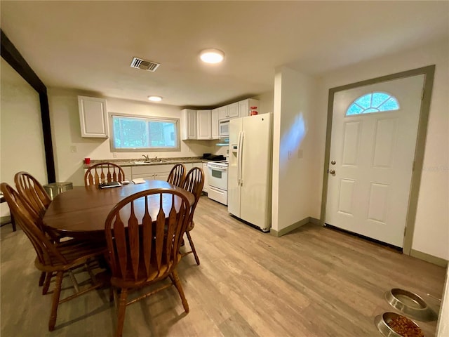 kitchen with sink, white appliances, light hardwood / wood-style flooring, and white cabinets