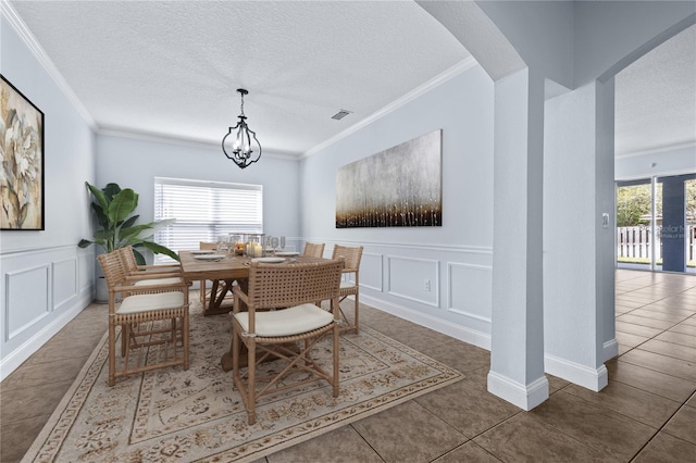 tiled dining area with ornamental molding, a chandelier, and a textured ceiling