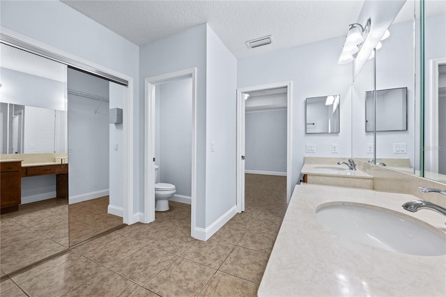 bathroom with vanity, toilet, tile patterned floors, and a textured ceiling