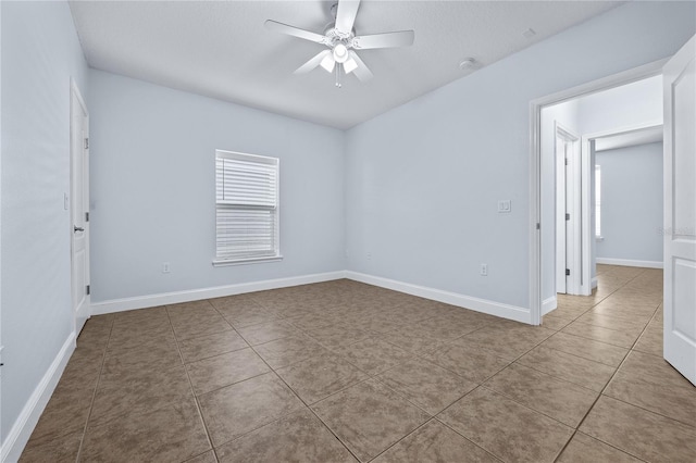 empty room with ceiling fan and light tile patterned floors