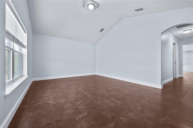 tiled spare room featuring lofted ceiling