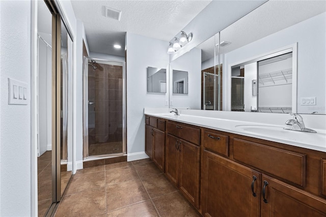 bathroom featuring vanity, tile patterned floors, walk in shower, and a textured ceiling