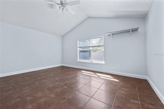 empty room with lofted ceiling, dark tile patterned flooring, and ceiling fan