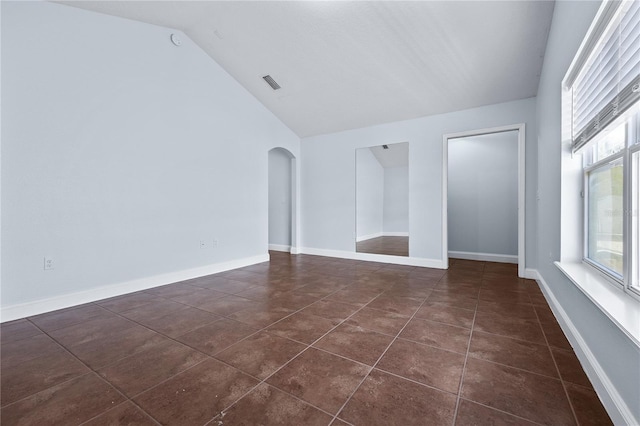 interior space with dark tile patterned flooring and vaulted ceiling