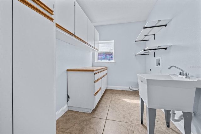 laundry area featuring hookup for an electric dryer, light tile patterned flooring, hookup for a washing machine, and cabinets