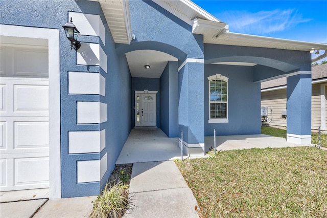 view of exterior entry featuring a lawn and a garage