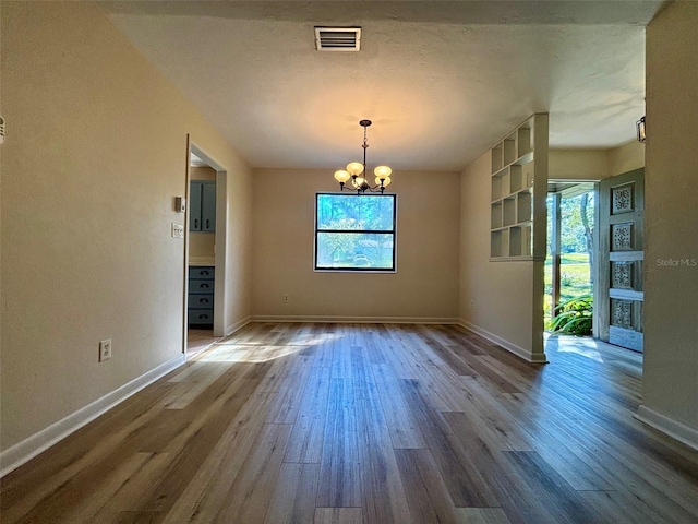 unfurnished dining area with hardwood / wood-style floors and a notable chandelier