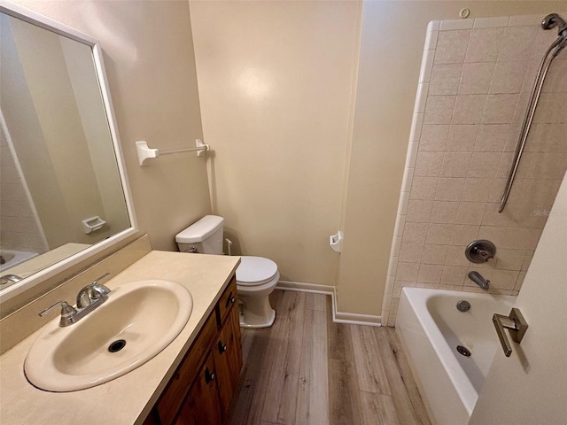 full bathroom with hardwood / wood-style flooring, vanity, tiled shower / bath combo, and toilet