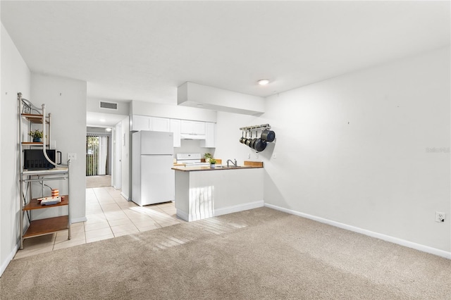 kitchen with sink, kitchen peninsula, light colored carpet, white appliances, and white cabinets