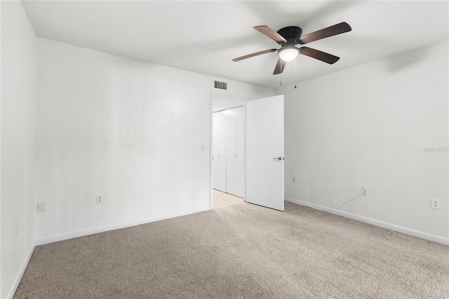 empty room featuring ceiling fan and light carpet