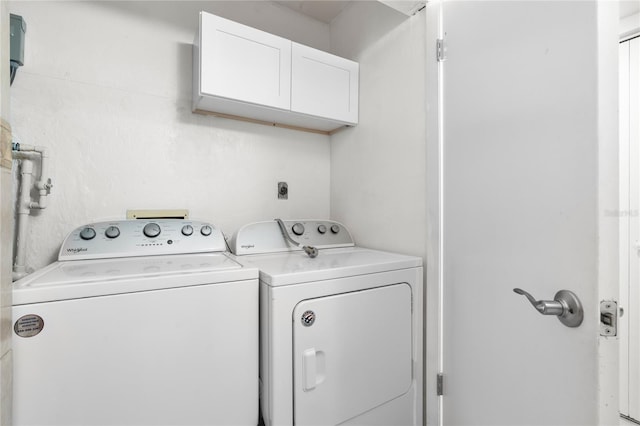 clothes washing area with washing machine and clothes dryer and cabinets