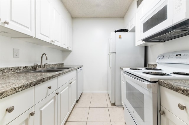 kitchen featuring white cabinets, light tile patterned flooring, sink, white appliances, and a textured ceiling