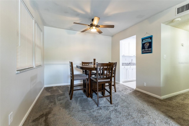 carpeted dining space featuring sink and ceiling fan