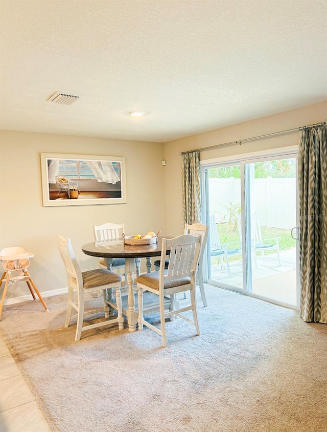 carpeted dining space with a textured ceiling