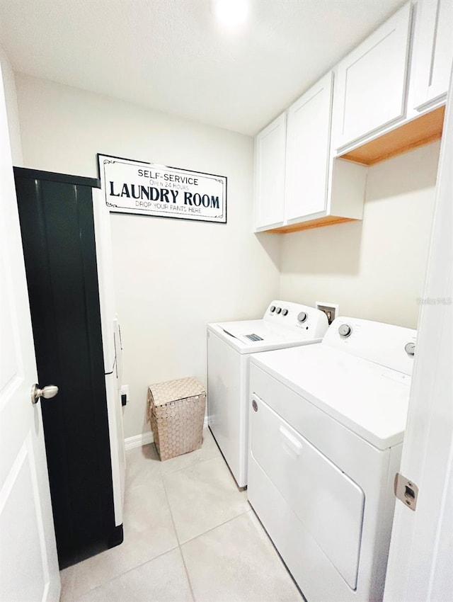 washroom with light tile patterned flooring, washer and dryer, and cabinets