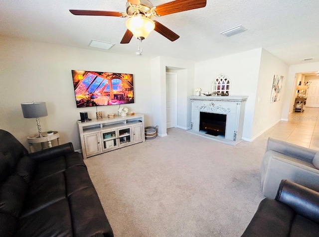 living room featuring light carpet, ceiling fan, and a textured ceiling