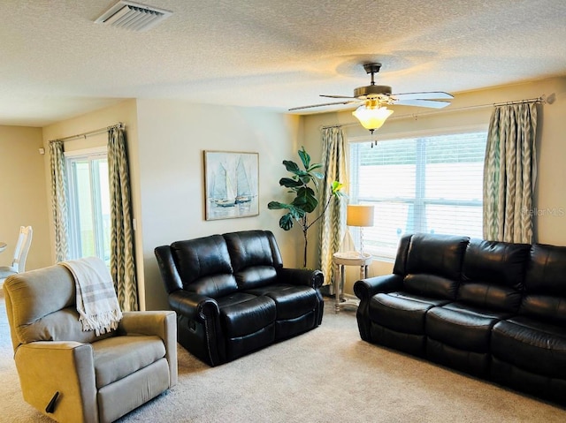 living room featuring ceiling fan, carpet floors, and a textured ceiling