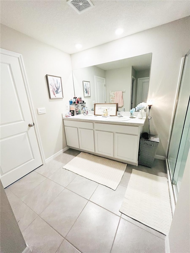 bathroom with tile patterned flooring, a shower with shower door, vanity, and a textured ceiling