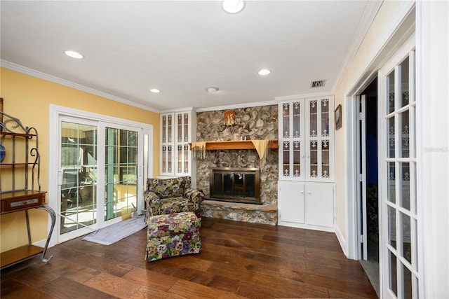 sitting room with a stone fireplace, dark hardwood / wood-style floors, and ornamental molding