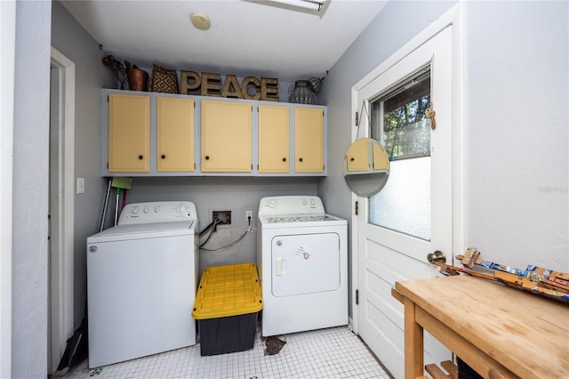 clothes washing area featuring cabinets, light tile patterned flooring, and washing machine and clothes dryer