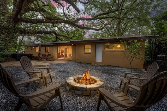 back house at dusk featuring a patio and a fire pit