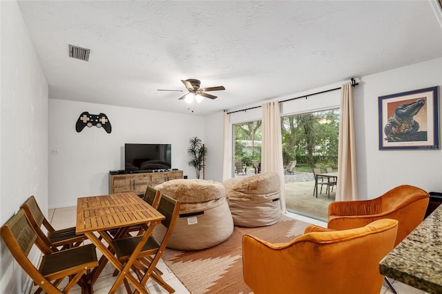 living room featuring ceiling fan and a textured ceiling