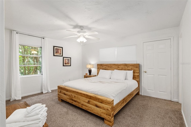 carpeted bedroom featuring ceiling fan and a textured ceiling