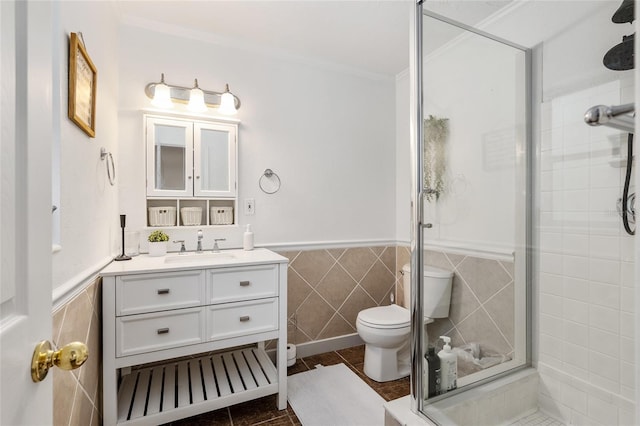 bathroom with toilet, tile walls, ornamental molding, vanity, and a shower with door