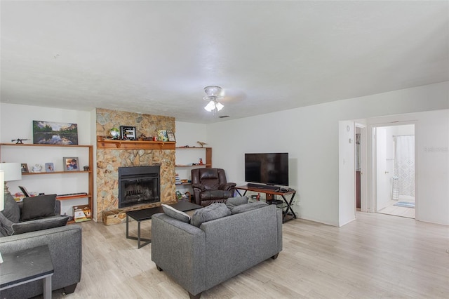 living room with ceiling fan, light hardwood / wood-style flooring, and a fireplace