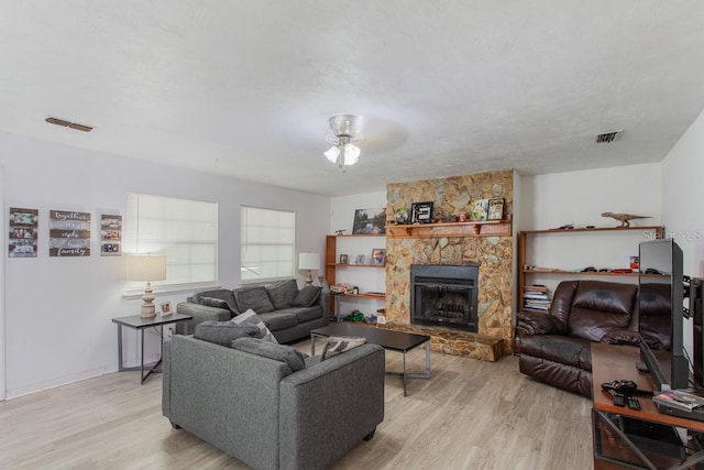 living room with a fireplace, light hardwood / wood-style floors, and ceiling fan