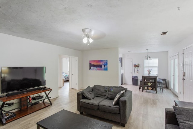 living room featuring light hardwood / wood-style flooring, a textured ceiling, and ceiling fan