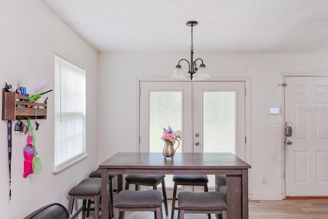 dining area featuring french doors, light hardwood / wood-style floors, a notable chandelier, and a healthy amount of sunlight